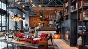 A modern lounge area with leather sofas, a wooden coffee table, and a decorative sculpture. - MOXY Seattle Downtown (Seattle)