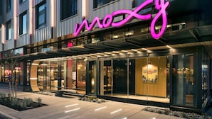 A modern hotel with a prominent neon sign, large glass windows, and a well-lit entrance. - MOXY Seattle Downtown (Seattle)