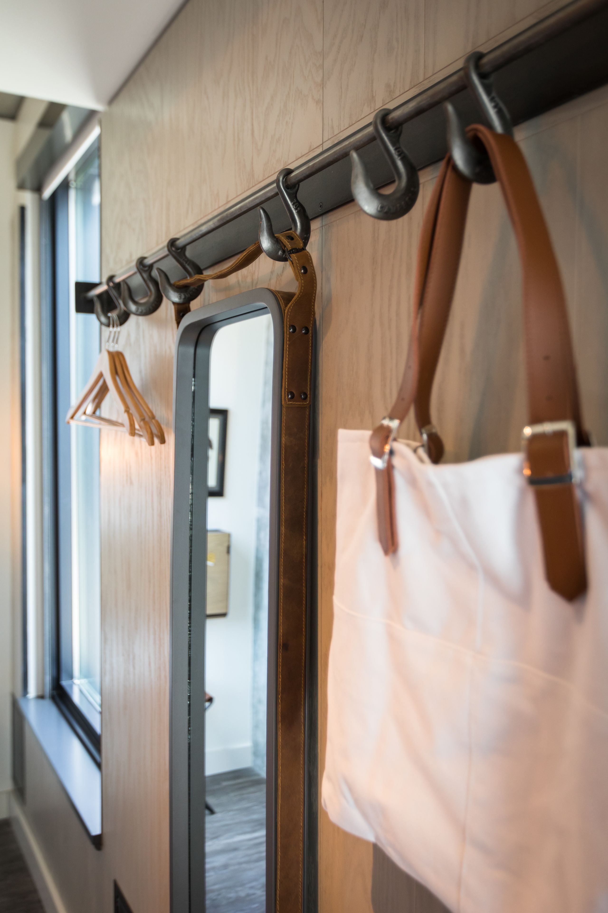 Ein Flur mit einem Garderobenschrank, der eine braune Ledertasche und einen hölzernen Kleiderbügel trägt.