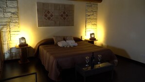 A cozy bedroom with a large bed, two bedside tables with lamps, a small table with glasses, and a decorative wall piece. - farmhouse I 5 SENSI (Vr) (modica)