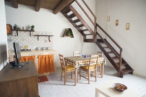 A kitchen with a dining table, chairs, and a wooden staircase.