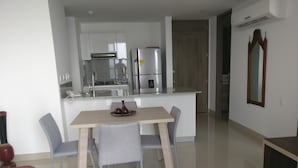 A modern kitchen with white cabinets, a stainless steel refrigerator, and a granite countertop.