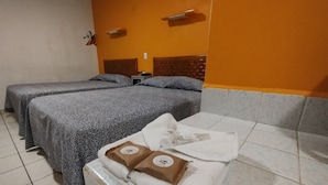 A hotel room with two beds, a sofa, and a small table. - Hotel Los Ciruelos (Oaxaca)