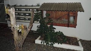 Una casa modelo con techo de metal corrugado, ventana de madera y un pequeño jardín con plantas.