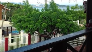 Un balcón con vistas a una piscina y follaje verde.