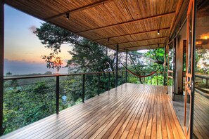 Eine Holzterrasse mit Blick auf das Meer und Bäume.