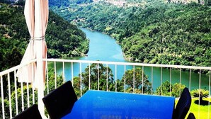 Ein Balkon mit Blick auf einen Fluss und umliegende Grünflächen.