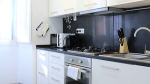 Eine moderne Küche mit weißen Schränken, einer schwarzen Arbeitsplatte, einem Herd, einem Backofen und einer Spüle.