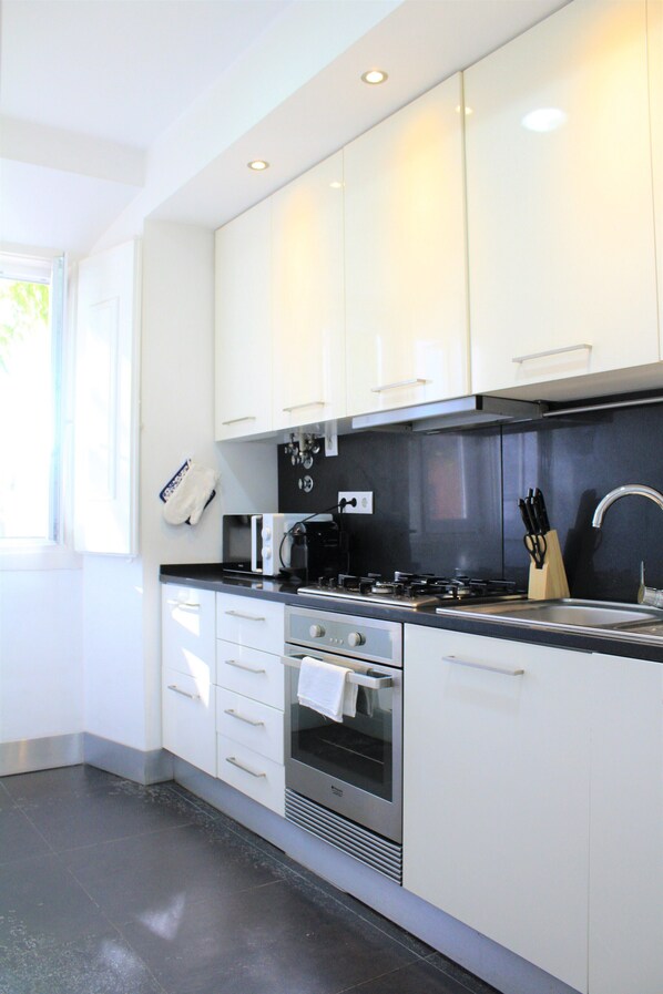 A modern kitchen with white cabinets, a black countertop, a stove, an oven, and a sink.