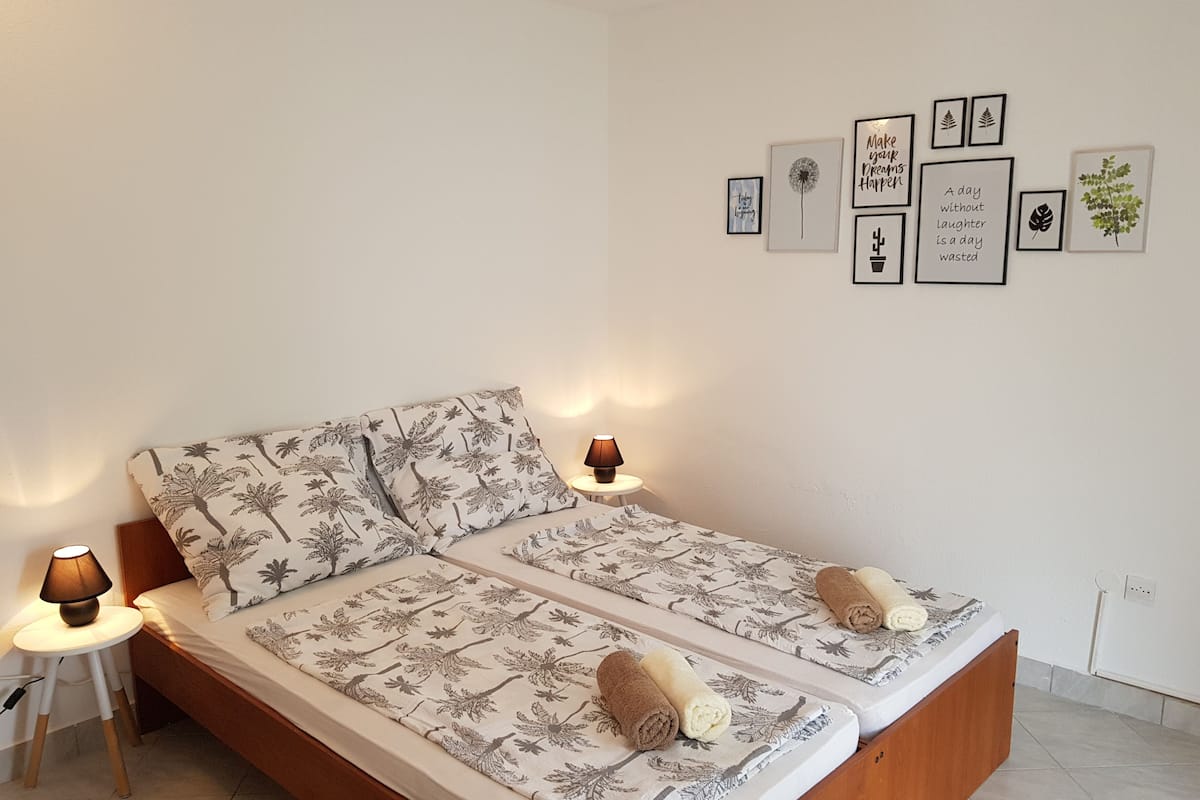 Een tweepersoonsbed met bloemenbeddengoed, twee bedlampjes en een muur met ingelijste inspirerende citaten.