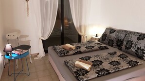 A bedroom with a bed, a bedside table with a lamp, and a window with sheer curtains. - Casa Nostra (Funtana)