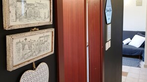 A hallway with a wooden door, a wall with framed black and white drawings, and a blue sign with text. - Casa Nostra (Funtana)