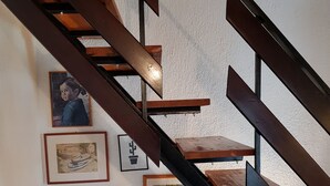 A staircase with wooden steps and black railings, surrounded by framed artworks and a chessboard. - Casa Nostra (Funtana)