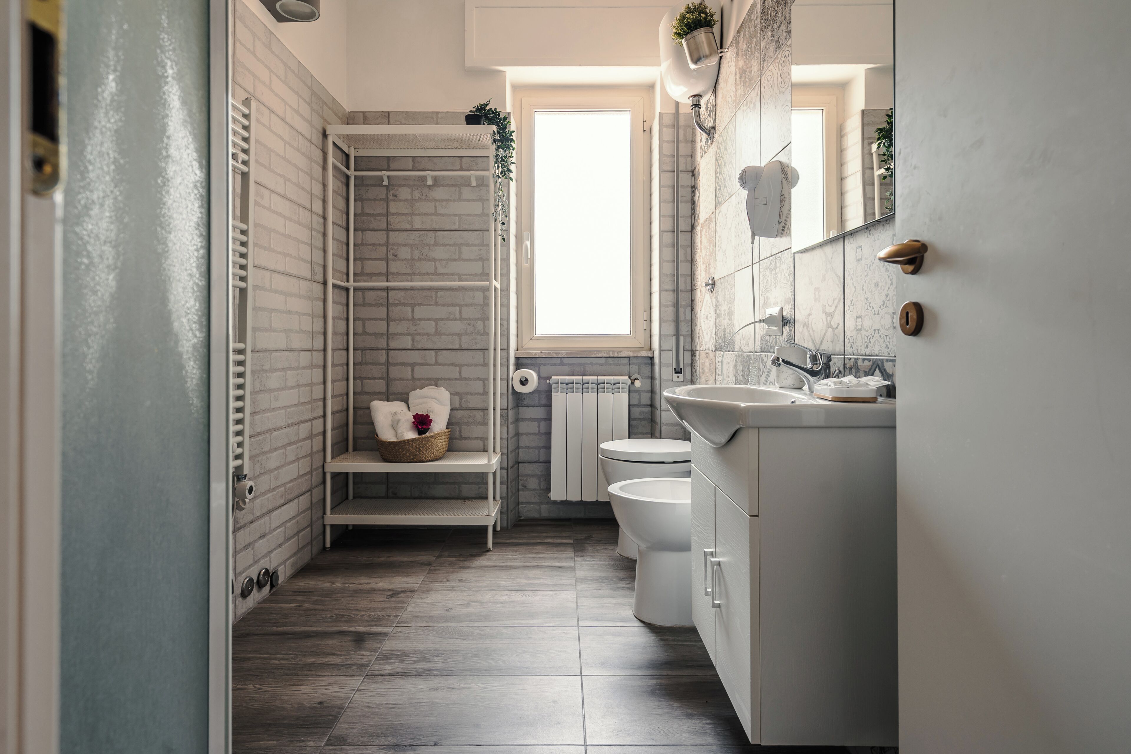 A bathroom with a shower, toilet, sink, and a window.