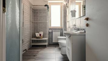 A bathroom with a shower, toilet, sink, and a window.