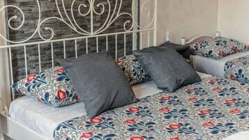 Un lit avec une couvre-lit à motifs, deux oreillers aux dessins différents et une tête de lit en métal.