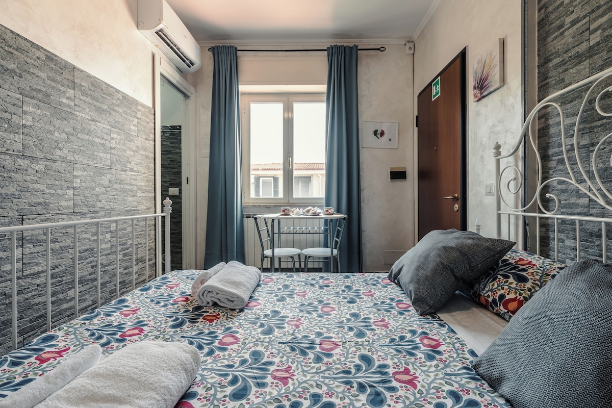 A bedroom with a bed, a small table, and a chair.