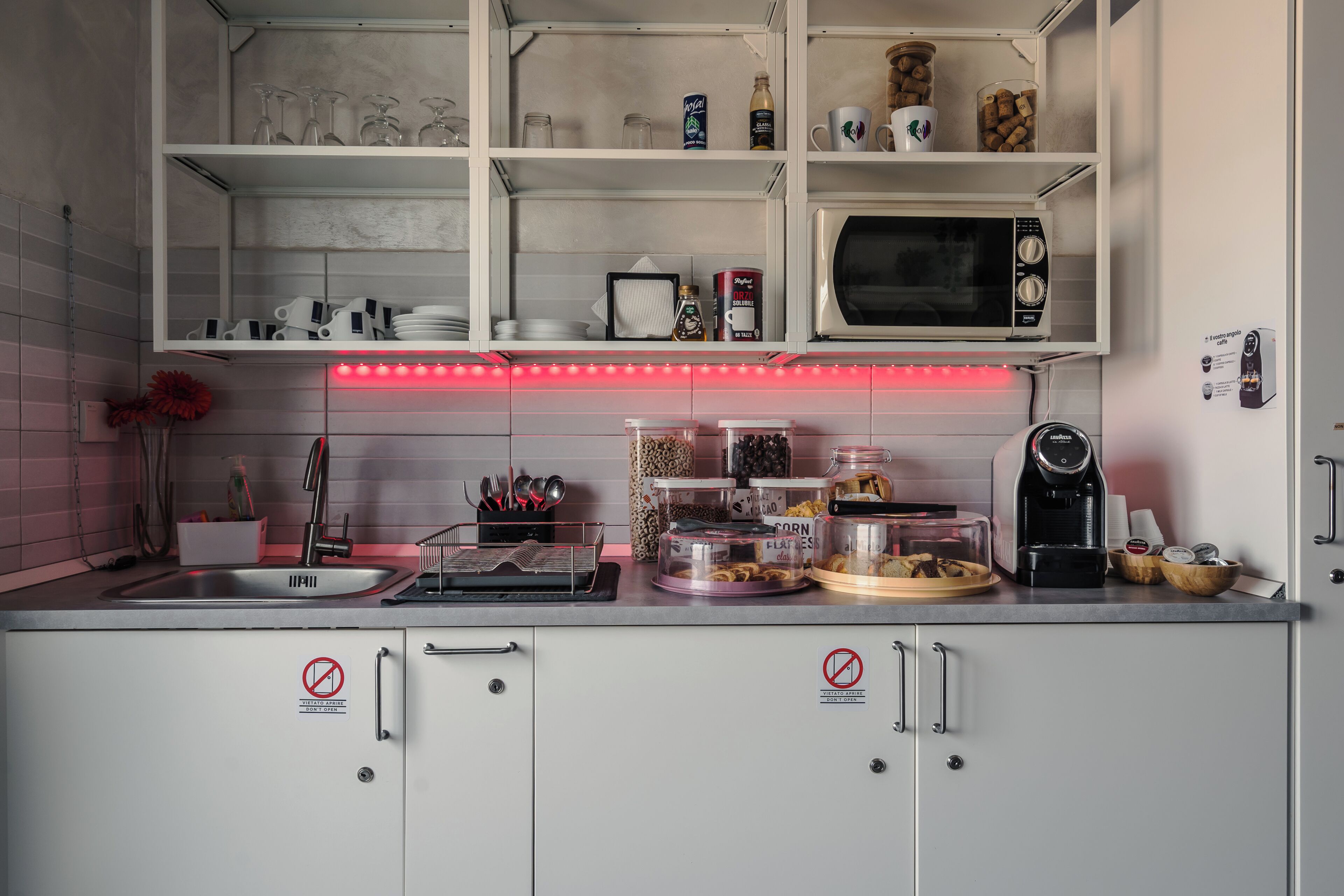 Een keuken met een magnetron, glazen op planken en een koffieapparaat.