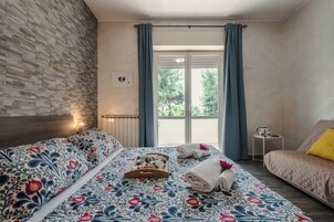 Et hotelværelse med en seng, en sofa, et lille bord og et vindue med gardiner.