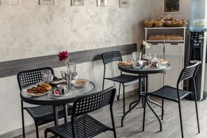 Un espace repas agrémenté d’un mur en marbre, d’un distributeur d’eau et d’une table mise avec des assiettes, des bols et des verres.