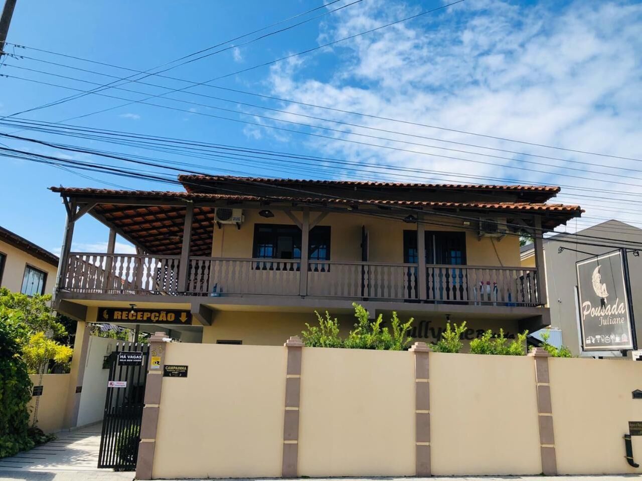 A two-story building with a balcony, a reception area, and a sign for 'Pousada Juliane'.