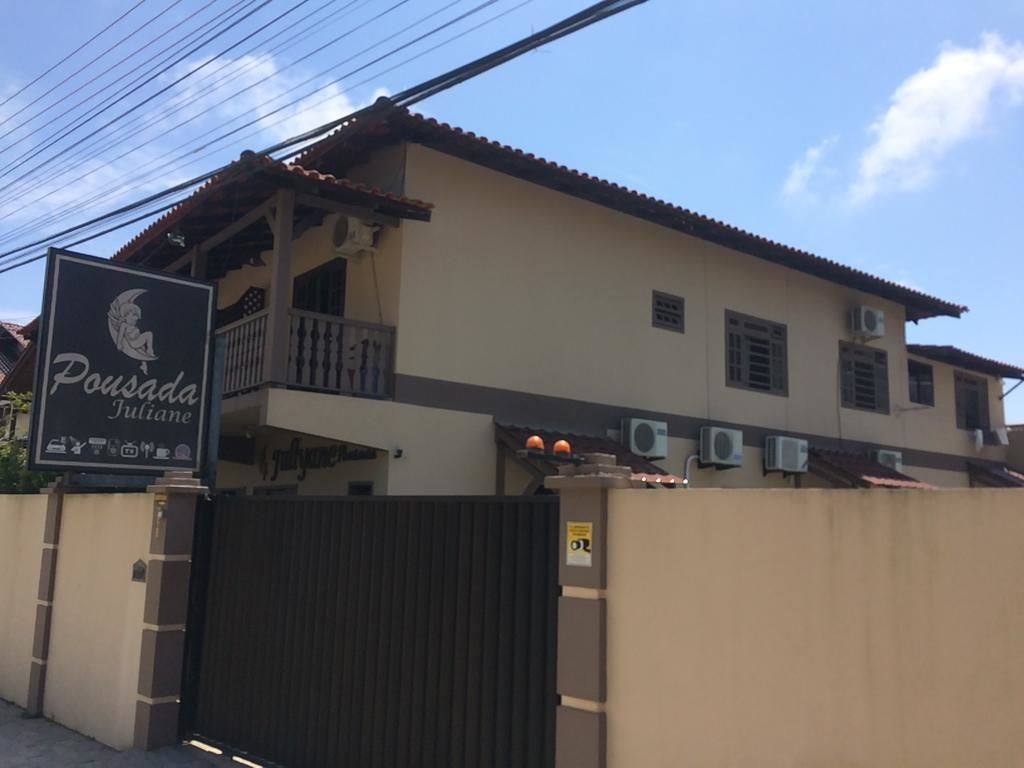 Un edificio de dos pisos con un letrero que dice 'Pousada Juliane' y una entrada con portón.