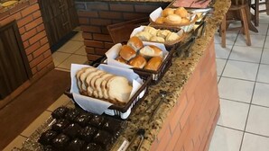 A breakfast buffet with various breads, pastries, and a coffee station. - Pousada Juliane (Penha)