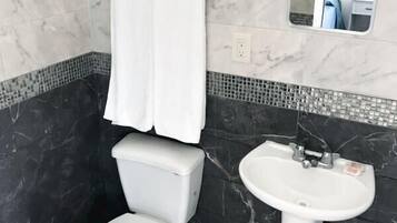 A bathroom with a toilet, sink, and mirror.
