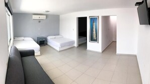 Una habitación de hotel moderna con una cama grande, un sofá, una mesita de noche pequeña y un televisor montado en la pared.
