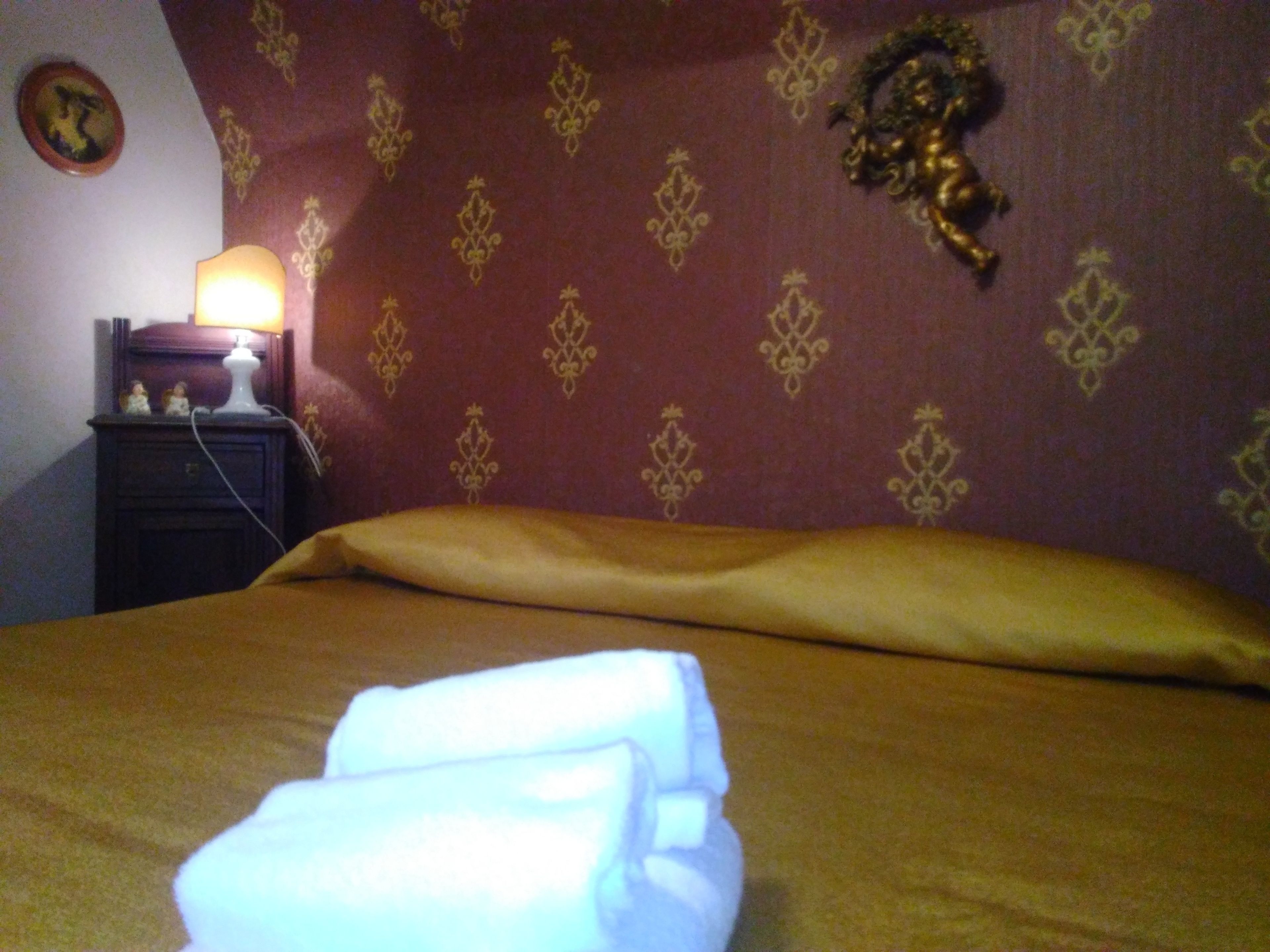 A neatly made bed with a gold-colored headboard and a decorative wall hanging.