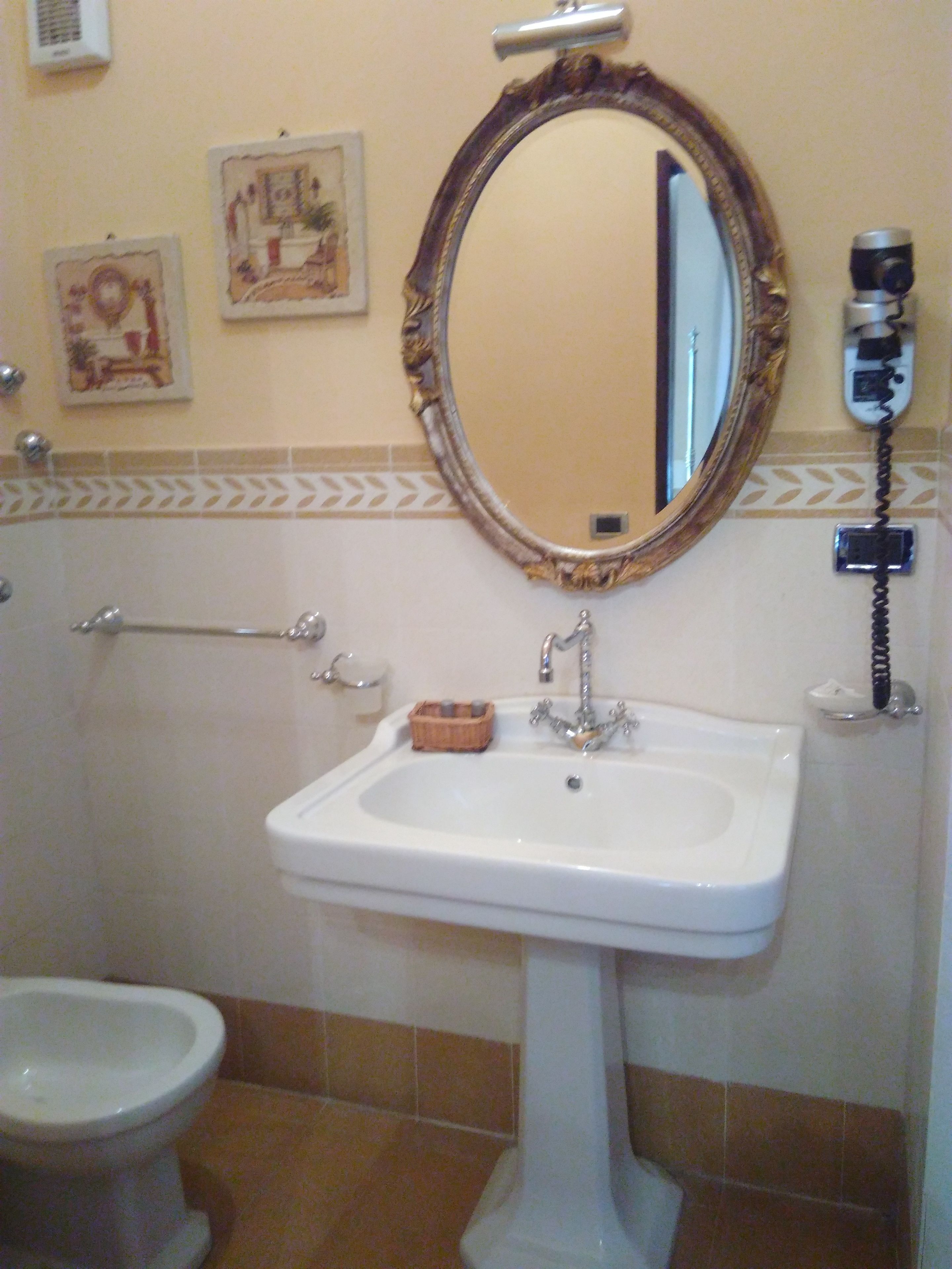 Un baño con lavamanos blanco, un espejo, inodoro y teléfono.