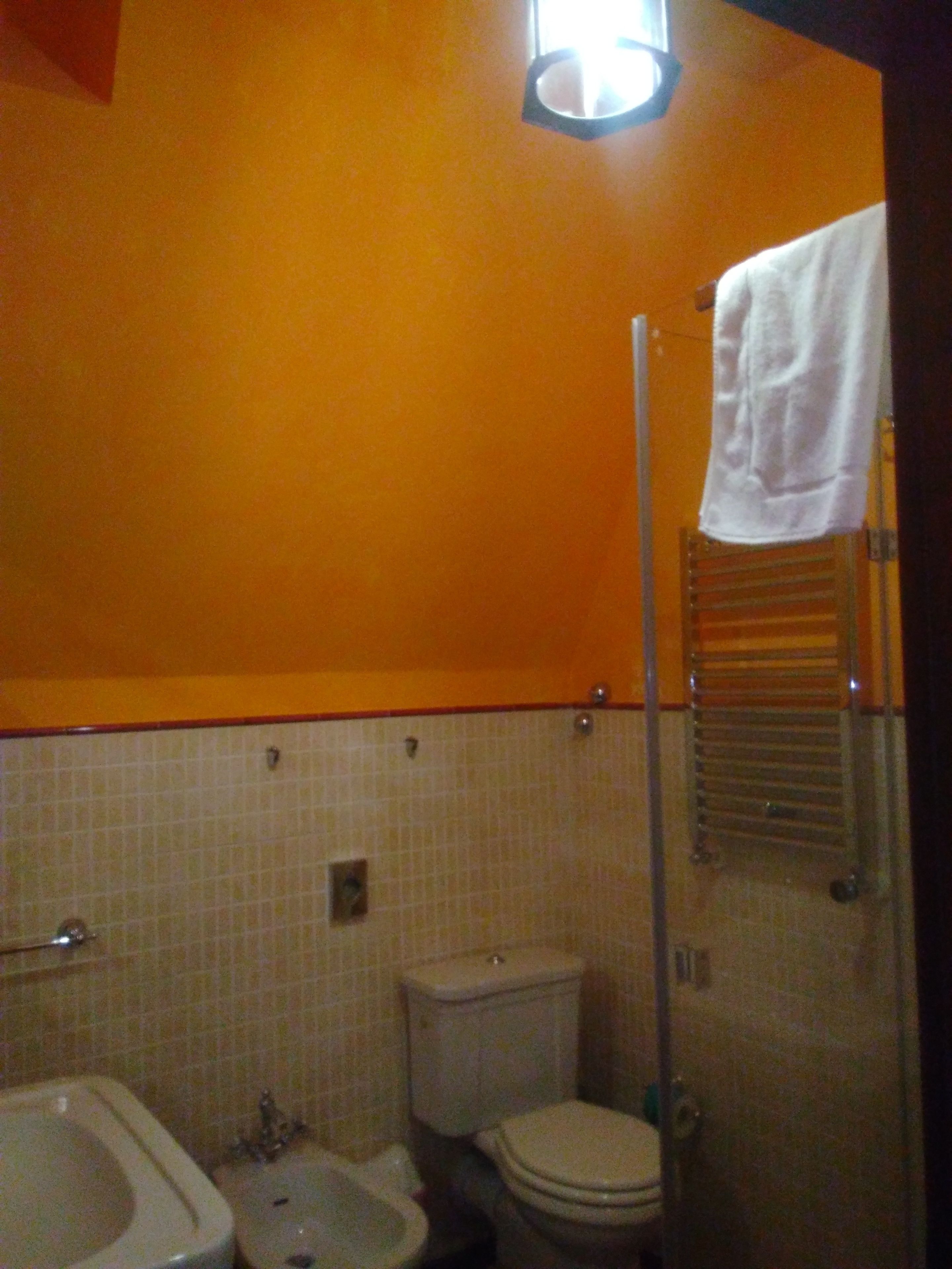 A bathroom with a bidet, toilet, and a towel rack.