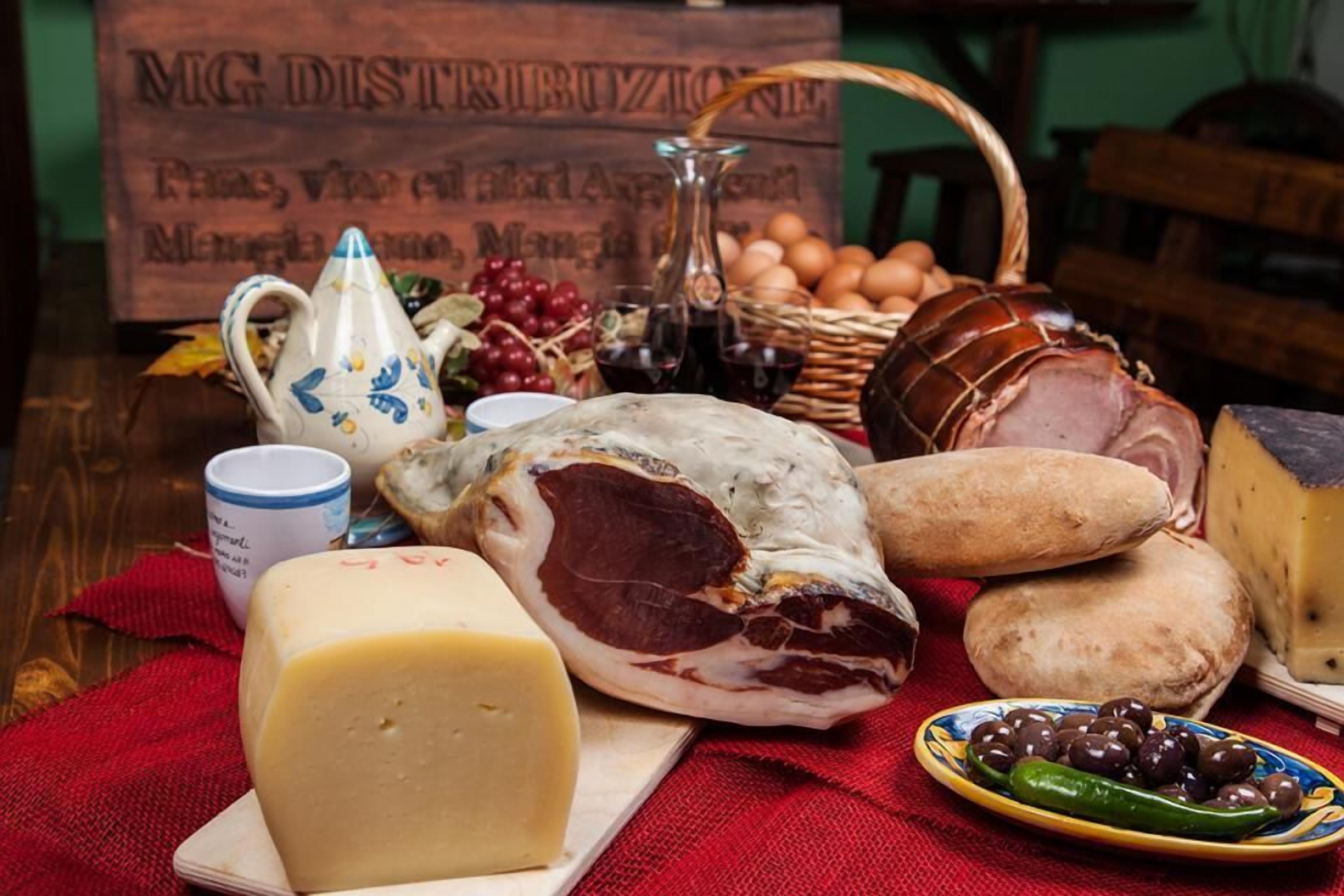 A variety of cheeses, cured meats, and olives on a wooden table.