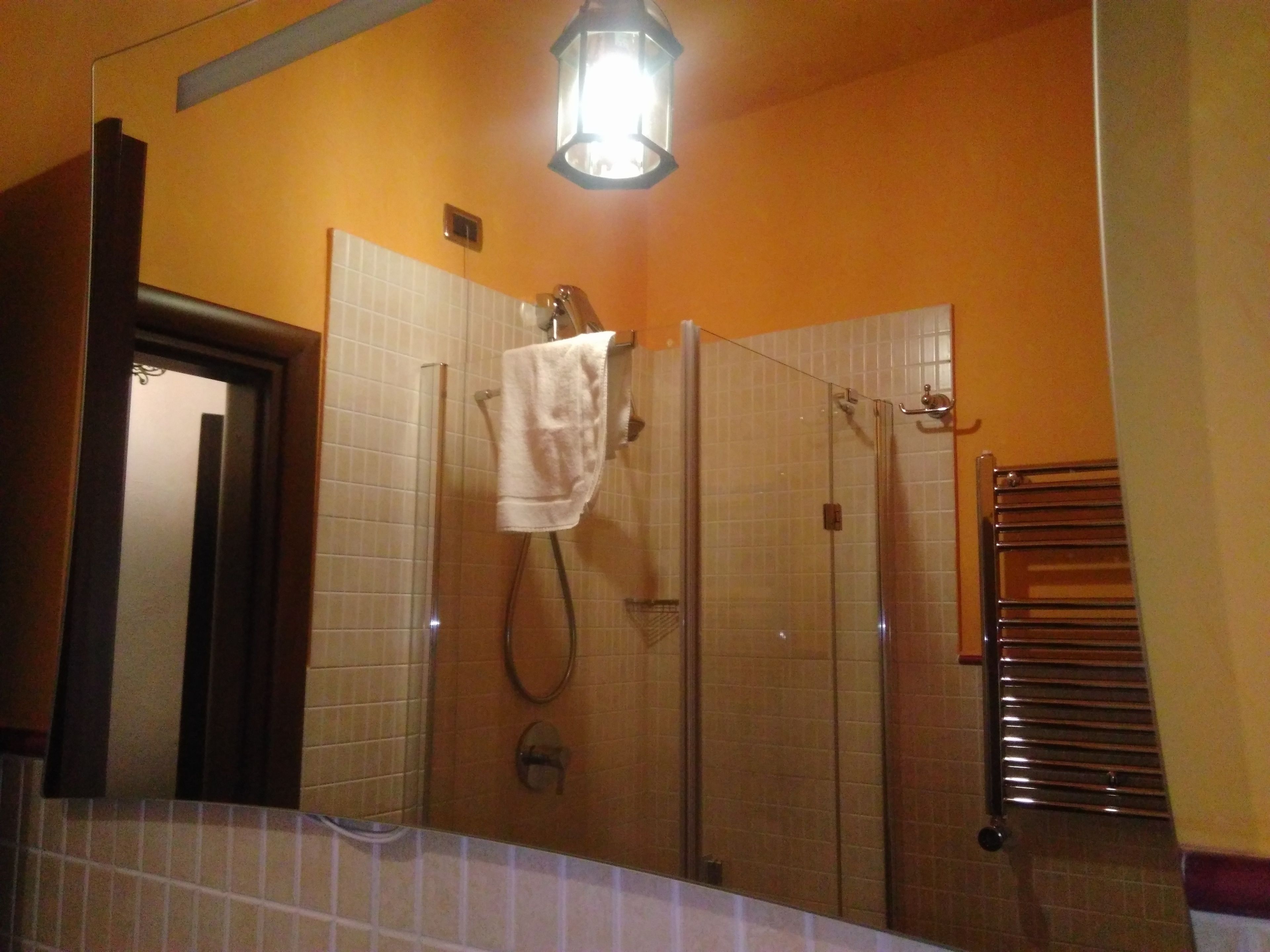 Un baño con ducha de vidrio, un perchero y una toalla colgada en la pared.