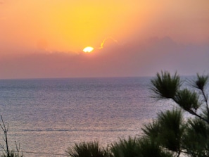 A sunset over the ocean with a clear sky. - Nirai Onna (Onna)