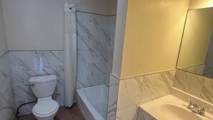 A bathroom with a toilet, bathtub, and sink. - World Motel (Lynwood)
