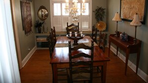 A dining room with a wooden table, chairs, a chandelier, and a mirror on the wall. - GASLIGHT COTTAGE  - Downtown Hendersonville (Hendersonville)