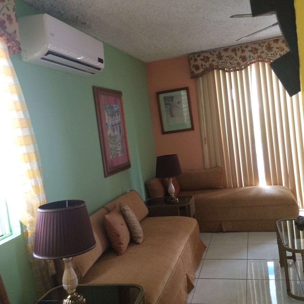 A living room with a sofa, a table, an air conditioner, and a lamp.