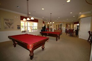 Une salle de billard équipée de deux tables de billard, d’un piano et d’un coin repas.