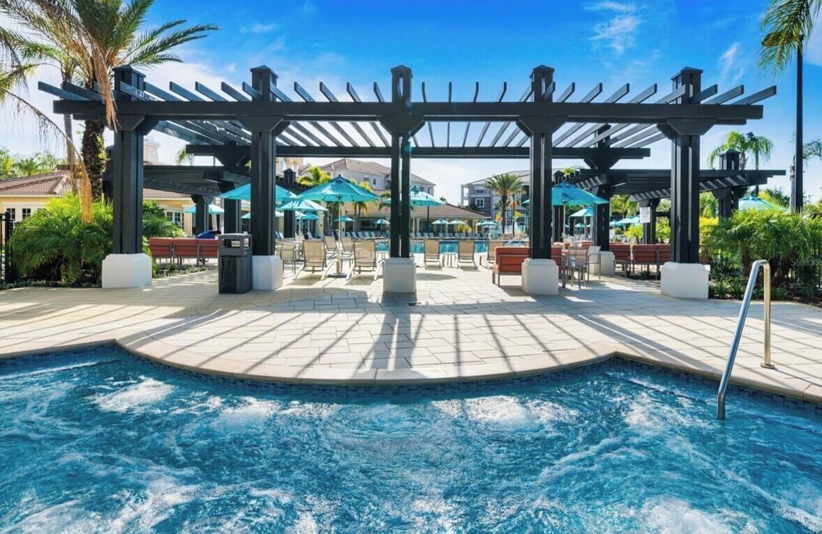 Un espace piscine agrémenté d’une pergola, de chaises longues et de parasols.