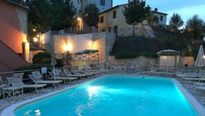 A swimming pool with lounge chairs and a stone wall.