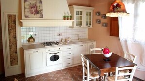 A kitchen with white cabinets, a stove, and a dining table with chairs.