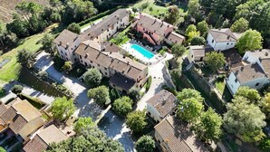 An aerial view of a residential area with multiple buildings, a swimming pool, and surrounding greenery.