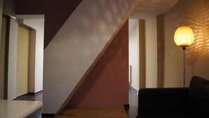 Un interior modern amb una escala, una làmpada i un sofà.
