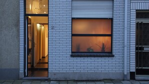 Edifici modern amb una finestra gran i una porta que condueix a un espai interior.
