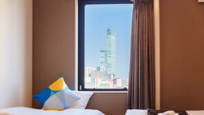 A hotel room with two beds, a window with a cityscape view, and a neatly made bed with a towel. - OKINI - DOYANEN HOTELS (Osaka)