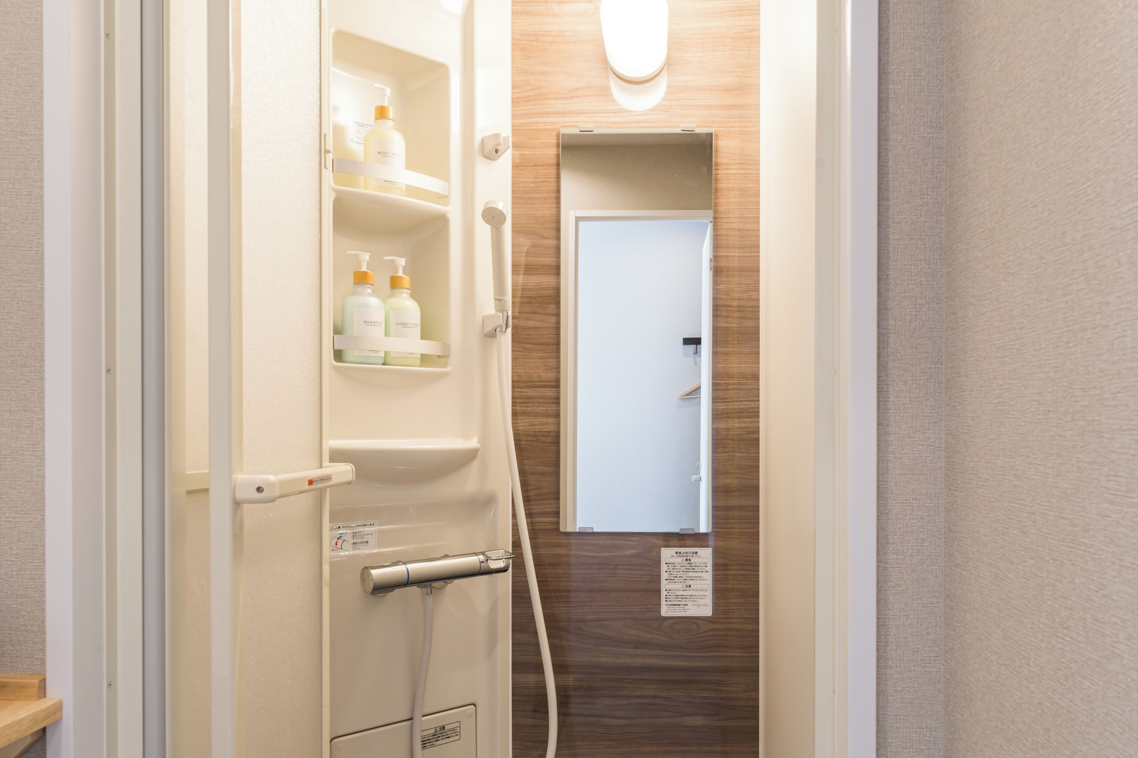 A bathroom with a shower, a toilet, and a shelf with toiletries.