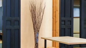 A room with a wooden table, a vase with branches, and dark wooden doors. - OKINI - DOYANEN HOTELS (Osaka)