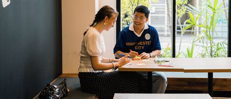 Two people sitting at a table with a blackboard in the background.
