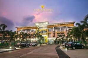 The exterior of Cupid Hotel Trang with multiple floors, palm trees, and a parking area. - Cupid Hotel (Palian)